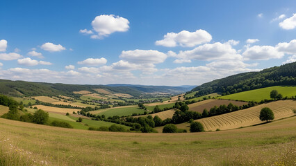 Obraz premium Rolling green hills and valleys under a blue sky with white clouds
