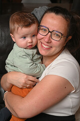 young child in his mother's arms, facing a black sofa