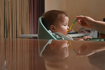young child in a chair eating with a spoon against the light