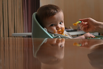 young child in a chair eating with a spoon against the light