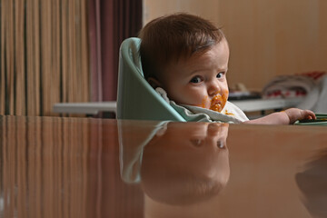 young child in a chair eating with a spoon against the light