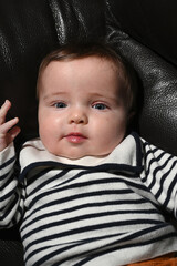 close-up of a young child wearing a sailor shirt sitting on a black sofa