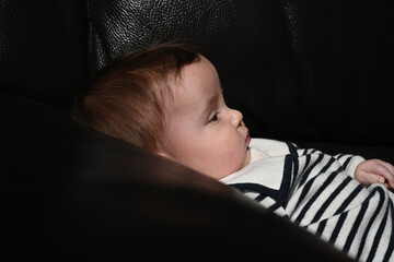close-up of a young child wearing a sailor shirt sitting on a black sofa