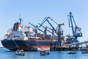 Fototapeta premium Close-up of a bulk carrier moored at a loading quay in the port of San Antonio, Chile, during cargo operations.