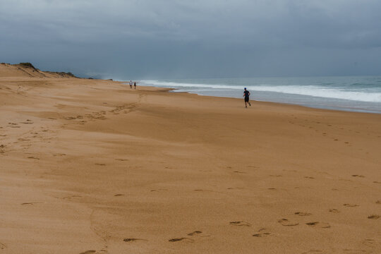 Runner on the beach in Labenne, Landes, France, under a cloudy sky.