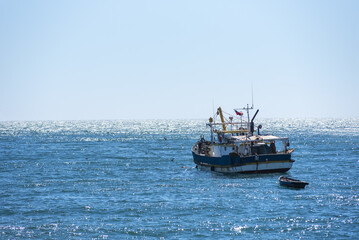 Naklejka premium Peaceful maritime scene with a moored fishing boat facing the reflective waters of the Pacific Ocean in San Antonio, Chile.