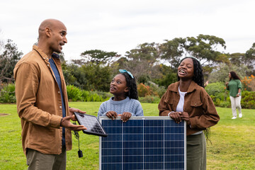 African American family dad showing small panel cable while two children holding big panel in park