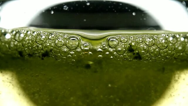 Close up of green liquid with bubbles rising in glass or Close up of bubbles forming on green liquid in container
