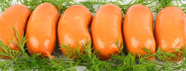 Row of fresh pork sausages garnished with green dill
