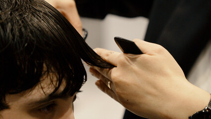Naklejka premium Close up of barber cutting hair with scissors