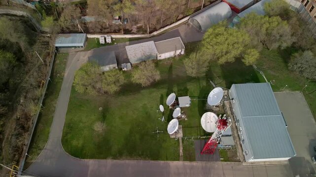 Aerial top-down view of a satellite communications station. Drone flight over large parabolic antennas and ground station equipment, telecommunications and global data transfer concept.