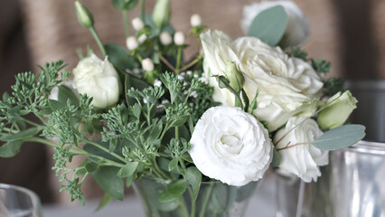 Elegant bouquet of white roses and lisianthus with green eucalyptus leaves in a glass vase