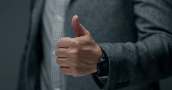 Close up of businessman in formal suit showing thumbs up gesture. Concept of approval, success, agreement, positive feedback, recommendation and business achievement.