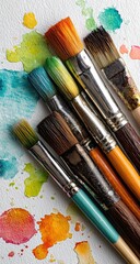 Fototapeta premium Close-up of paintbrushes atop colorful watercolor paint splatters