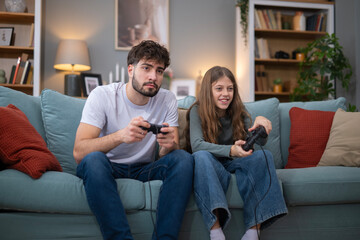 Obraz premium Brother and sister playing video games on sofa at home