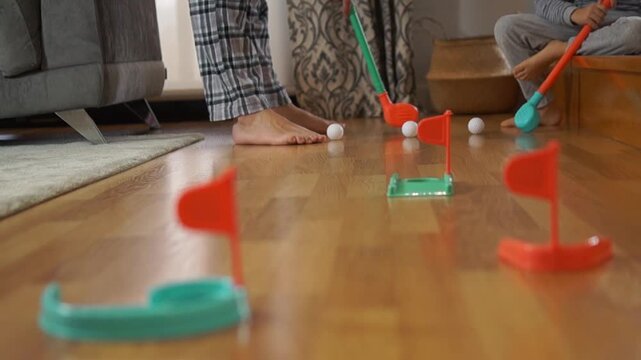 A dad and his little boy play together with colorful golf toys on a sunny morning, capturing authentic moments of parenthood and joy.