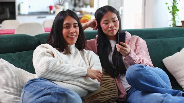 Young female friends watching tv together on a couch