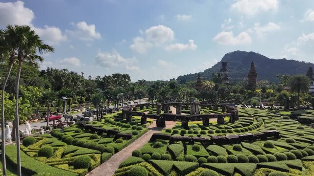 geometrically trimmed topiary maze at Nong Nooch Tropical Garden, Thailand, with ancient stone structures and palm trees
