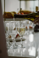 Fototapeta premium Pouring sparkling wine or champagne into flute glasses at a luxury wedding banquet or celebration