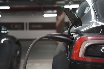 Close-up of a black electric vehicle charging in an underground parking garage
