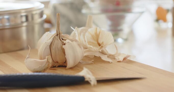 Camera is slowly zooming in and reframing head of garlic on cutting board, emphasizing textures