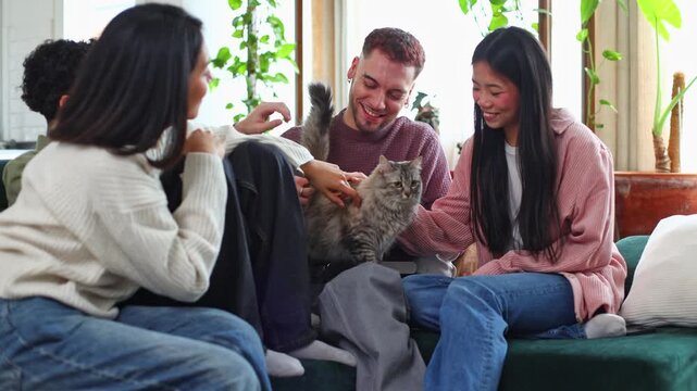 Group of happy friends petting a cat on the couch