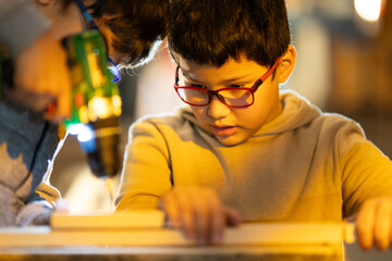 Young boy learning woodworking skills with adult