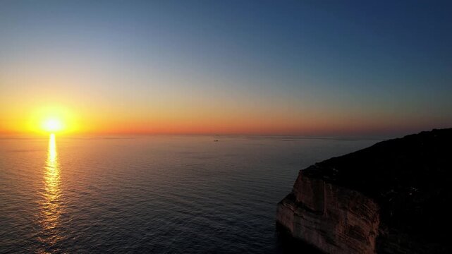 Aerial drone view of the Highest point of Malta at Dingli Cliffs, beautiful lush green grass and rock formations with a steep drop to the sea at sunset, golden hour. Sun giving the golden glow