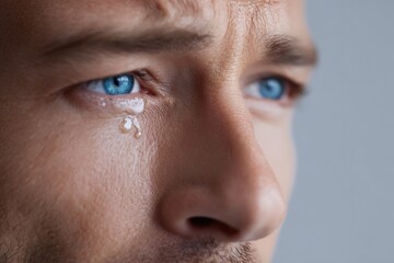 Fototapeta premium Close-up of emotional adult caucasian male with tearful blue eyes