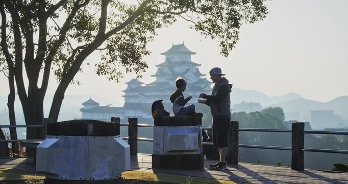 Silhouette of father and son playing rock, paper scissors in front of ancient Japanese castle
