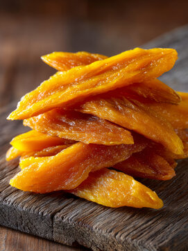 Stack of dried mango slices on rustic wooden background
