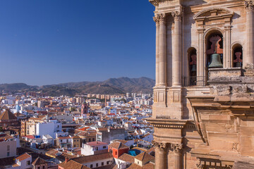 Obraz premium Close up of the Malaga Cathedral bell tower with stone columns and city view