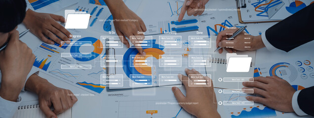 A group of professionals engages in a collaborative meeting, analyzing various data charts and...