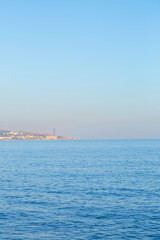 Fototapeta premium Mediterranean sea horizon and Malaga coastal landscape under clear evening sky during sunset with mountain silhouettes in Andalusia Spain with calm water surface.