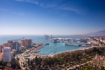 Port of Malaga industrial harbor with maritime vessels ferry and industrial cranes in La Malagueta district viewed from a high viewpoint under a clear blue sky in Andalusia Spain coastal area. © Sodel Vladyslav