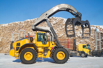 Loading logs with a special loader.Timber products warehouse on a specialized site.