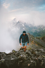 Obraz premium Active man hiker climbing foggy mountains travel in Norway healthy lifestyle extreme vacations in Lofoten islands adventure tour outdoor, traveler mountaineering solo endurance and freedom in the wild