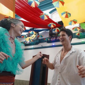 Borogod&oacute; brasileiro: Casal celebra o Carnaval de Tiradentes. Jovens rindo e dan&ccedil;ando sob decora&ccedil;&atilde;o de sombrinhas coloridas de frevo em ambiente hist&oacute;rico mineiro. Alegria e movimento.