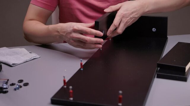 Man doing home improvement, building new flat pack modern furniture, assembling wooden shelving with cam locks and dowels, creating diy project for indoor living space, close-up, slow motion.