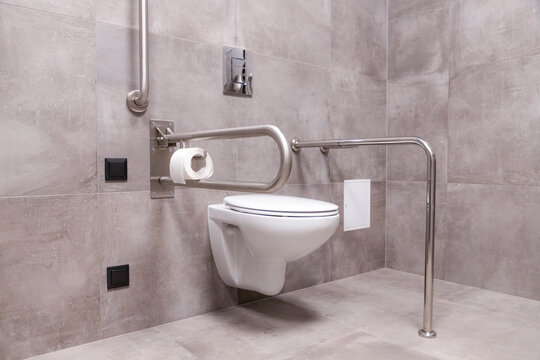 Modern toilet in the bathroom adapted for people with disabilities with grab bars
