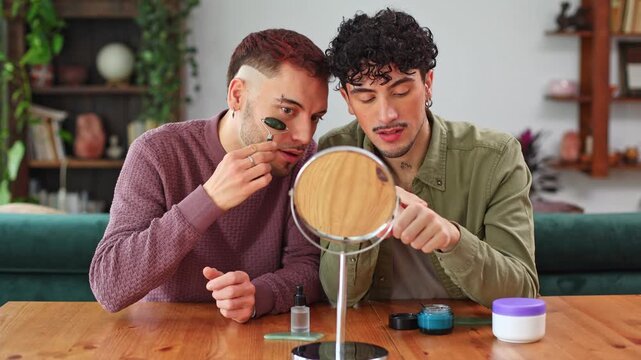Gay couple applying makeup and using jade roller together