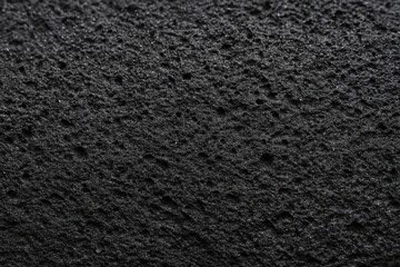 Fototapeta premium Macro close-up of dark porous lava rock with scattered holes and pits