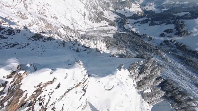 High Angle Aerial View Looking Down Steep Snowy Mountin Cliff to Valley