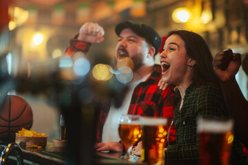 Friends enjoying sports in a bar cheering and celebrating