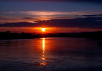 A serene sunset over a calm body of water with vibrant orange hues.