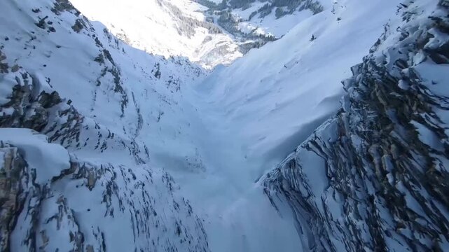 Cinematic FPV Drone Dive Down into a Deep Snow Covere Mountain Gorge