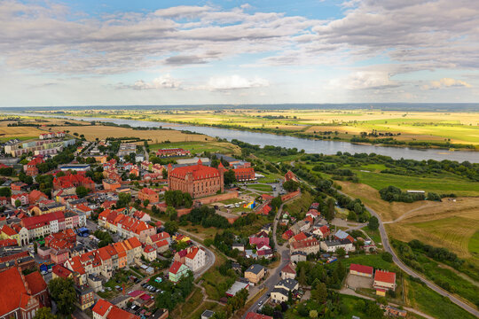 Aerial view of Gniew Castle in Poland, medieval Teutonic fortress above Vistula River, red brick stronghold surrounded by historic town and countryside landscape