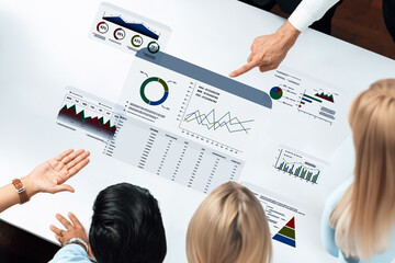 Business professionals engage in an insightful discussion while examining digital graphs and...