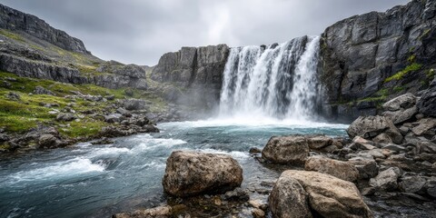 Mountain waterfall cascading into rocky river with misty landscape