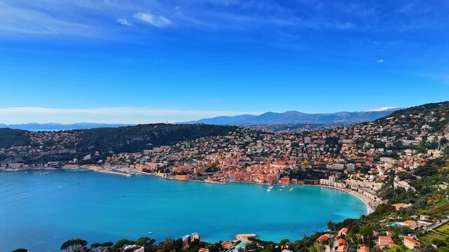 Rocky shore of the Mediterranean Sea with multiple buildings in the lush greenery. Drone footage at the picturesque coast of Nice, France on sunny day.